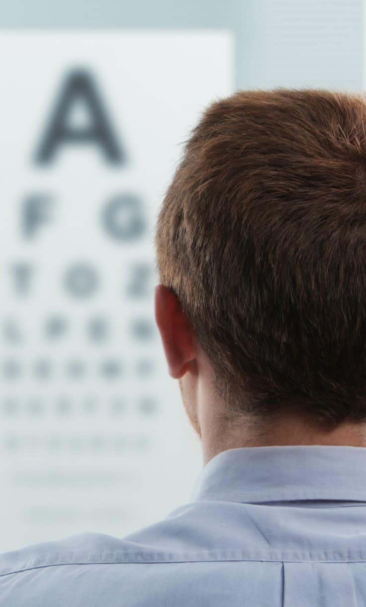 Snellen chart in the background of a clinic with a man having his vision tested